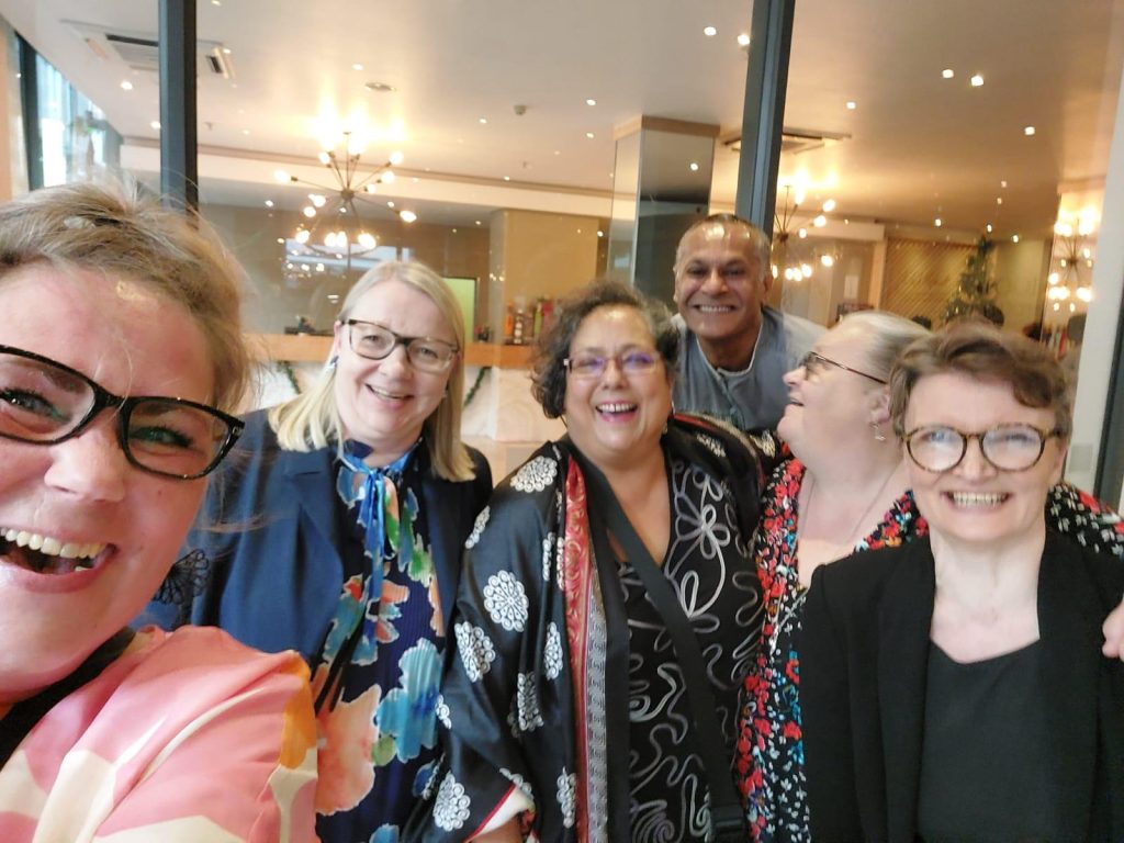 Suomen delegaation jäsenet hymyilevät ryhmäkuvassa.
