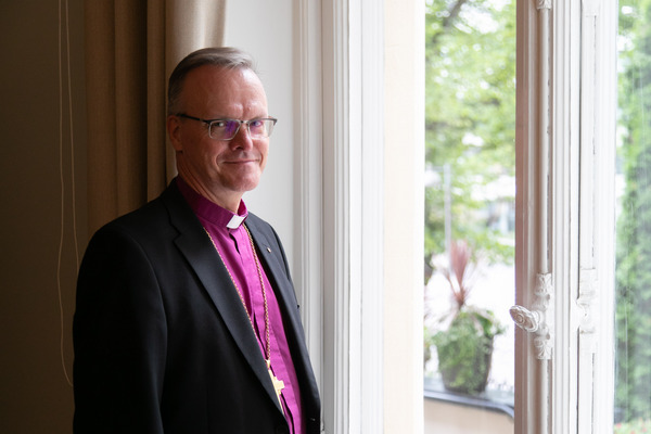 Puolikuva ikkunan äärellä seisovasta ja kameraan päin katsovasta Tapio Luomasta.