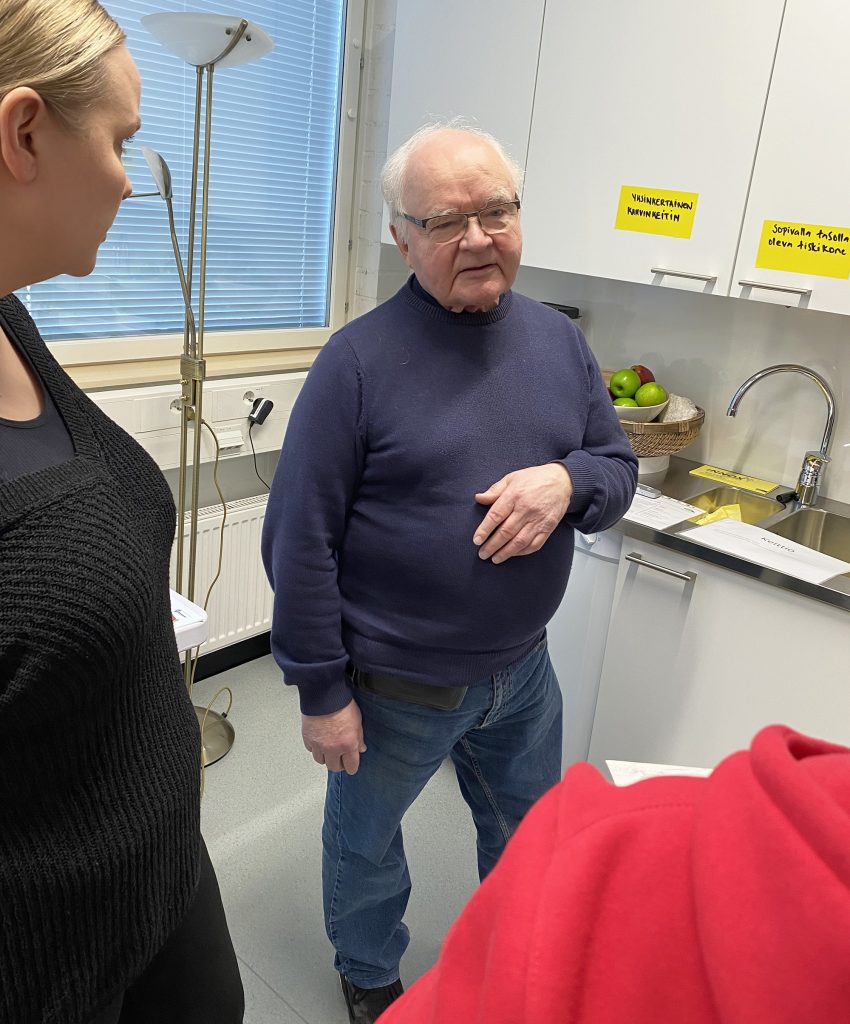 Nuorempi henkilö katsoo vanhempaa henkilöä, joka puhuu.