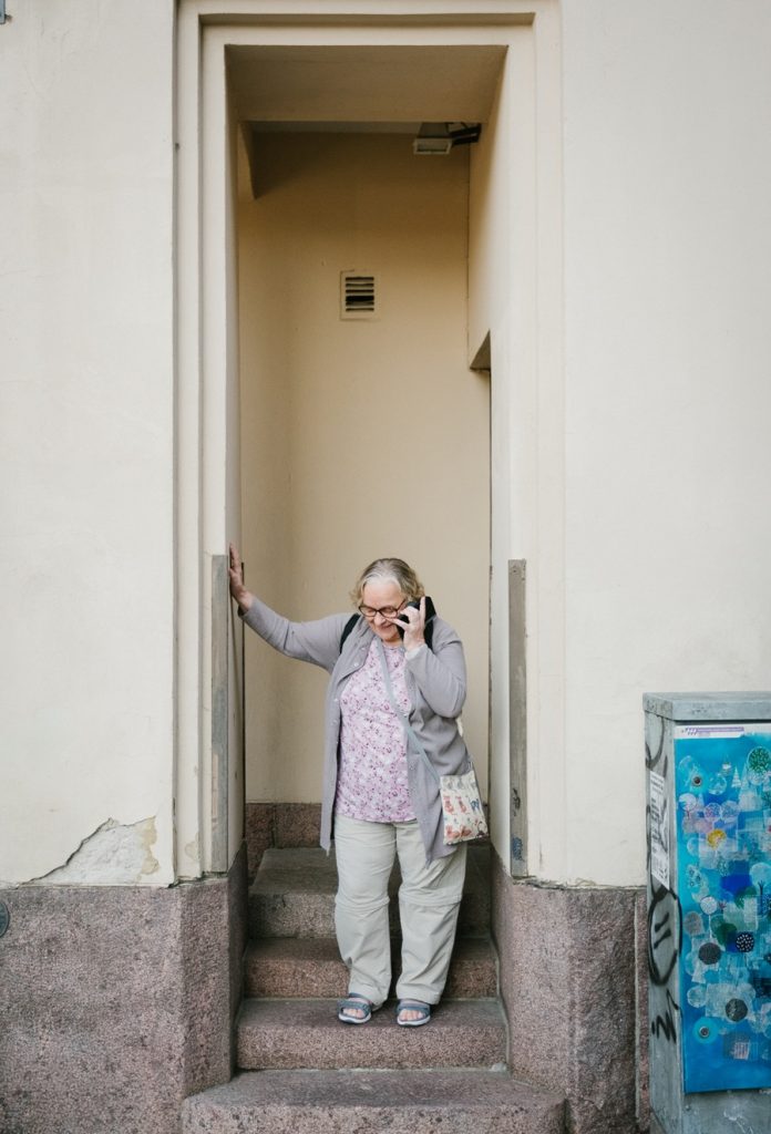 Seniori seisoo porttikongissa ja puhuu puhelimeen.