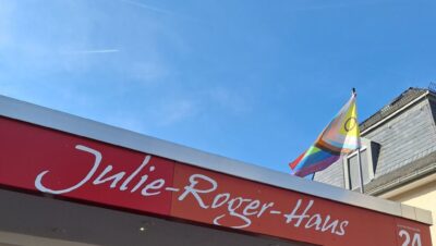 Julie-Roger-Haus-hoivakodin sisäänkäynti, jonka katolla liehuu sateenkaarilippu.