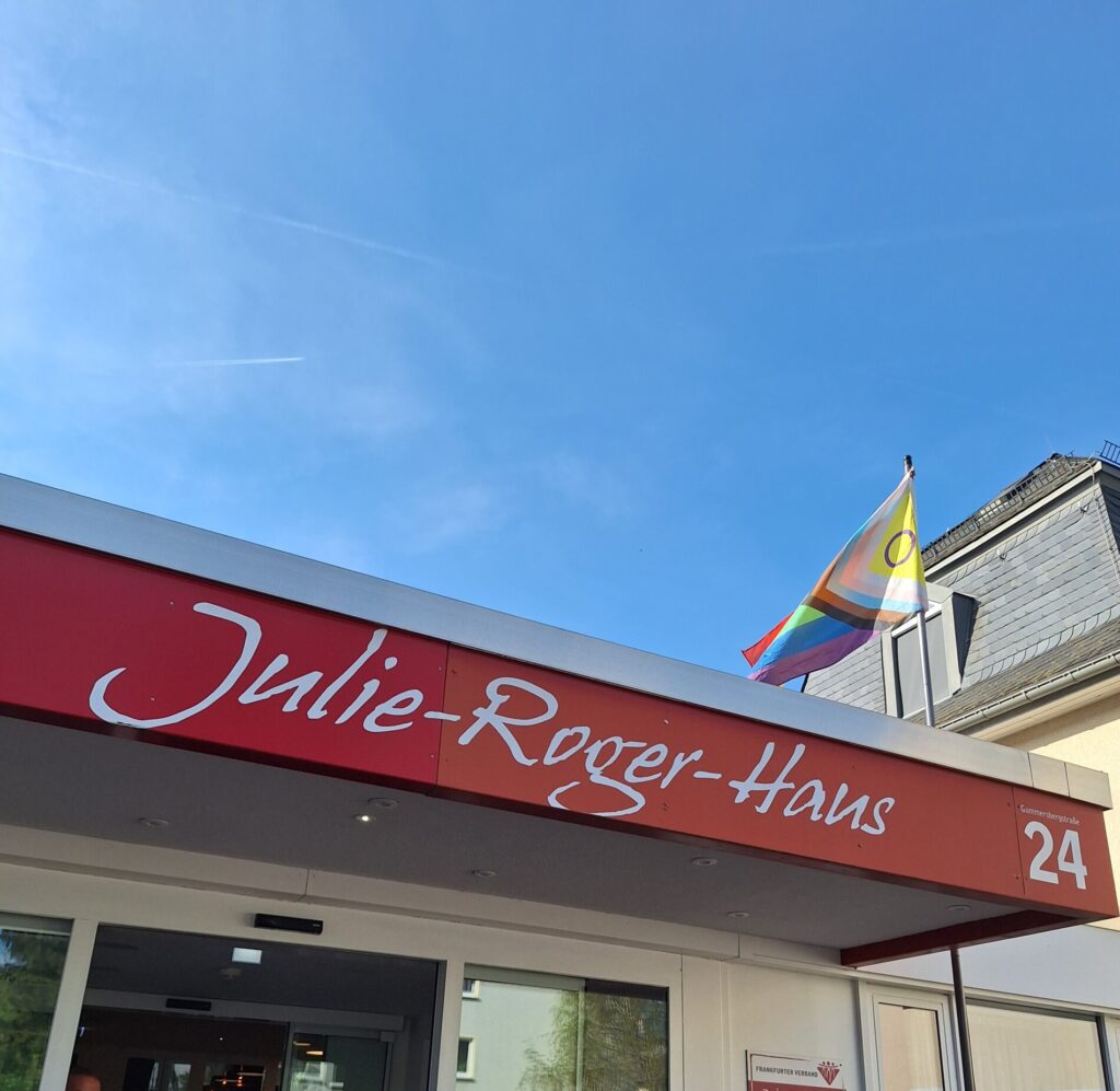 Julie-Roger-Haus-hoivakodin sisäänkäynti, jonka katolla liehuu sateenkaarilippu.