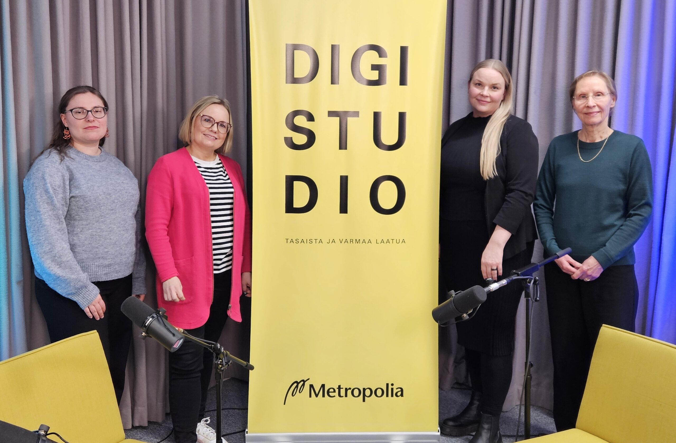 Neljä henkilöä hymyilee kameralle, vierellään rollup. Rollupissa teksti Digistudio, Metropolia amk.